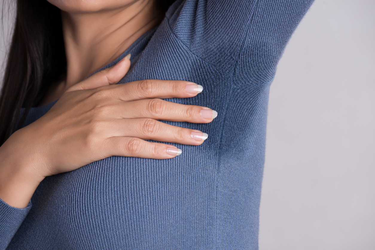 Close-up asian woman with hyperhidrosis sweating. Young asia woman with sweat stain on her clothes against grey background. Healthcare concept.