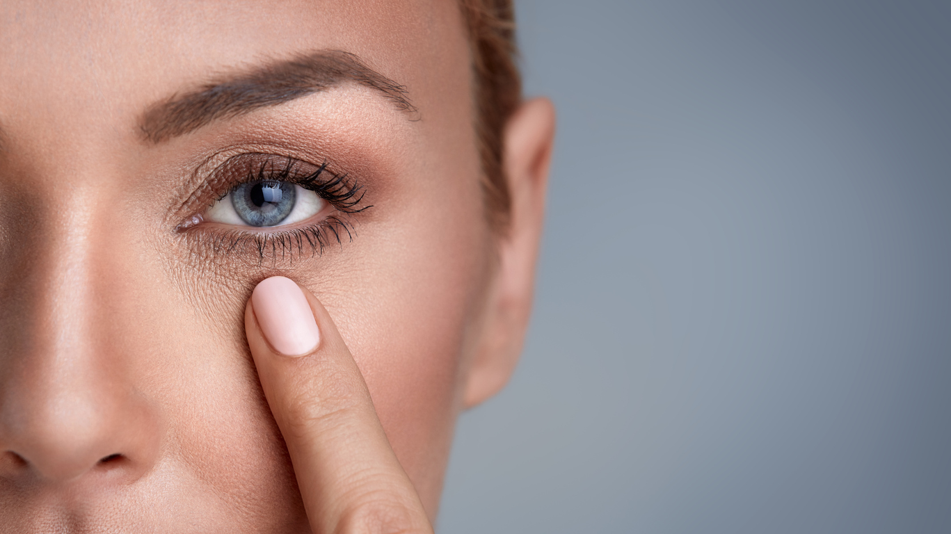 woman checking wrinkles around the eyes, close up